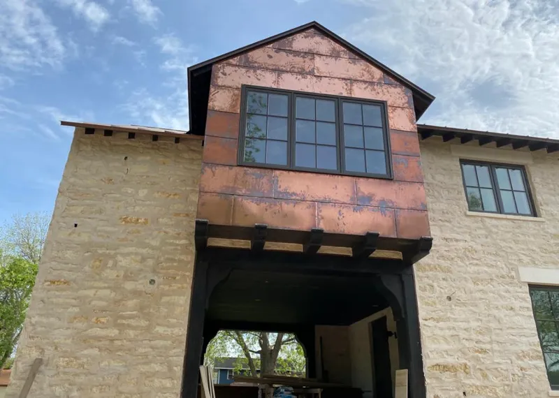 Copper metal panel facade on a stone building for Roof Repair in Lennox